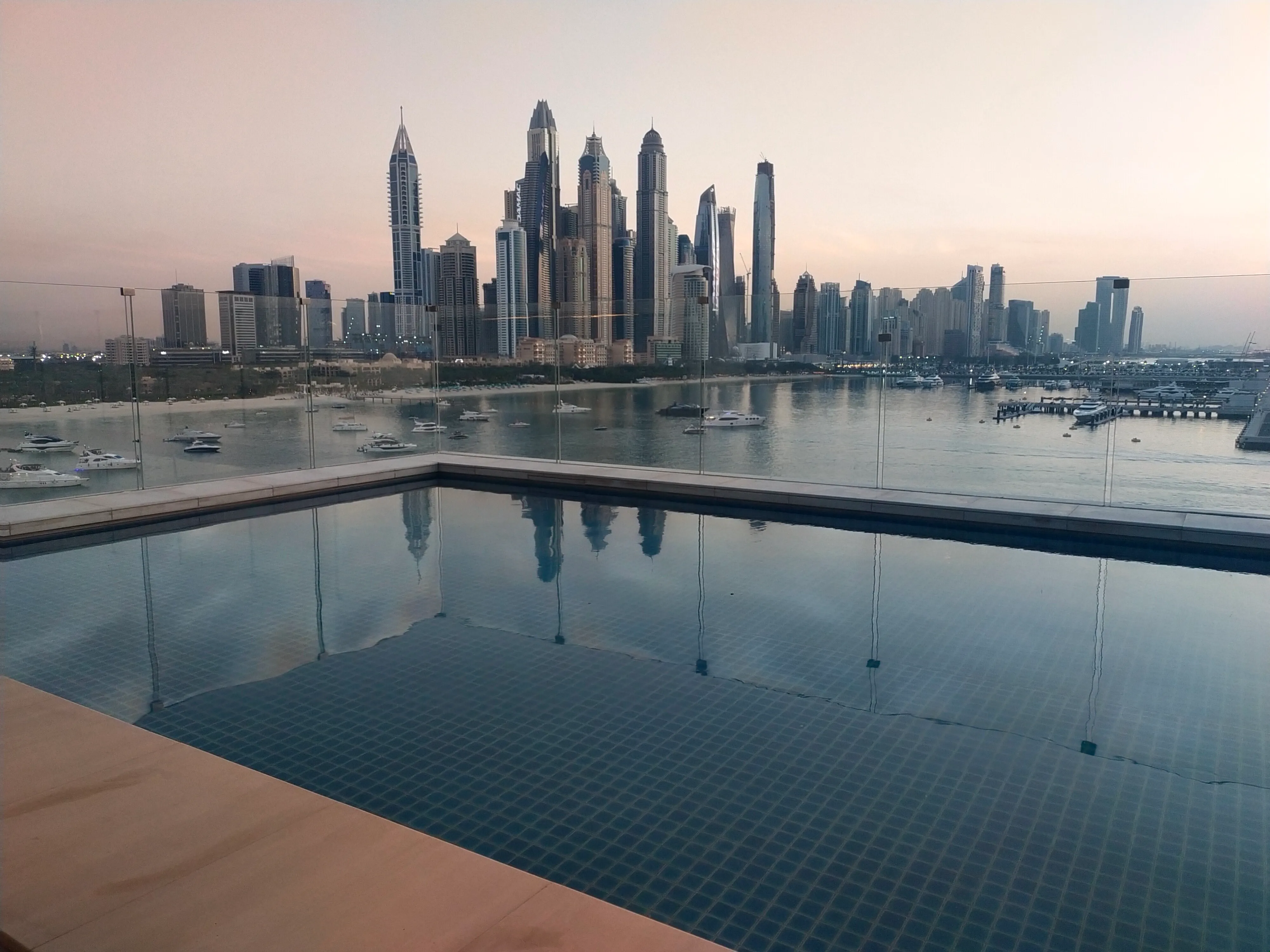 Nocny widok na zwarte wieżowce Dubaju z oświetlonymi oknami i balkonami, miejskie światła i gęsta zabudowa.